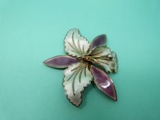 A silver brooch in the form of a flower set with cream and purple enamel,