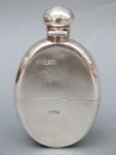 A George V oval shaped hallmarked silver hip flask with pull off cup and bayonet cap,