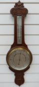 A George V period carved oak aneroid barometer and thermometer combination with silver dial,