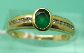 An 18ct gold ring set with an oval apple green emerald and channel set diamonds in a row to each