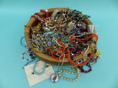 A round wooden bowl containing costume jewellery, silver bangle, agate necklace,