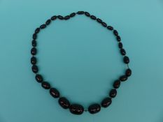 A cherry amber necklace of graduated oval beads,