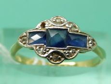 An 18ct gold ring set with a square cut sapphire and two rectangular cut sapphires surrounded by