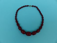 A cherry amber necklace of graduated oval beads,