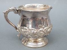 An Edward VII hallmarked silver pedestal cream jug with embossed floral decoration, Chester 1908,
