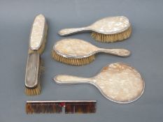 A hallmarked silver dressing table set comprising hand mirror and four various brushes,