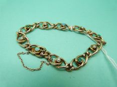 An Edwardian 9ct gold bracelet with knot design set with seed pearls and turquoise (11.