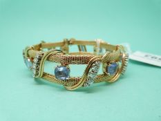 An 18ct gold bangle set with seven cushion cut cornflower blue sapphires each approximately 2ct and