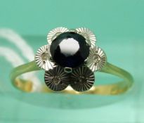 A yellow metal ring set with a round cut sapphire and white sapphires in a cluster (size K)