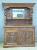 An oak carved sideboard with bevelled mirror back and carved figural supports,