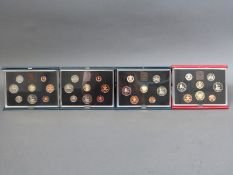 Four Royal Mint deluxe cased coin collections comprising 1983, 1984,