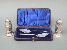 A cased pair of hallmarked silver spoons and a pair of hallmarked peppers