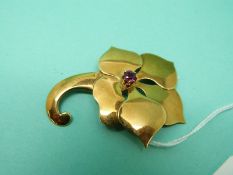 An 18ct gold brooch in the form of a flower set with a ruby, 12.