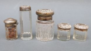 Four hallmarked silver lidded cut glass dressing table bottles and a further example marked