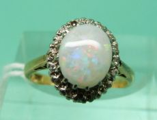 An 18ct gold ring set with an opal cabochon surrounded by diamonds (size J)