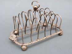 A Georgian hallmarked silver six-slice toast rack with gadrooned base raised on four ball feet,