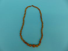 An amber necklace of oval egg yolk coloured beads,
