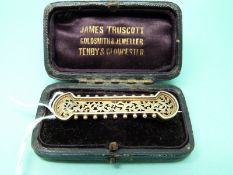 A Victorian yellow metal bar brooch with pierced decoration in original James Truscott Gloucester