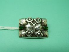 A silver brooch by Georg Jensen c1908 of floral design set with two green cabochons
