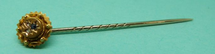 A 15ct gold stick pin set with a sapphire and two diamonds