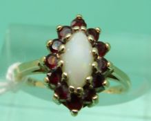 A 9ct gold ring set with an opal cabochon surrounded by garnets (size H)