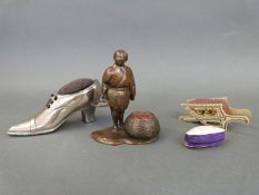 Three various pin cushions including a bronze gentleman with basket,