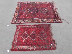 Two Afghan rugs on red ground (164 x129cm and 105 x 78cm)