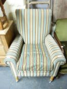 A modern upholstered armchair with turned wooden legs and chrome castors