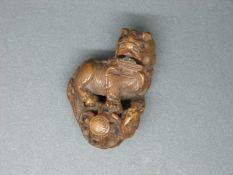 A Japanese carved wooden netsuke of a Dog of Fo,