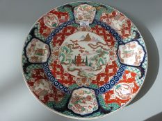 A Japanese Imari charger decorated with a central scene of a temple by the coast in mountainous