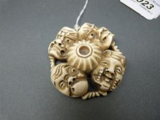 A Japanese Meiji period signed ivory netsuke in the shape of four Noh masks