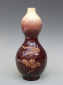 A Japanese earthenware double gourd vase decorated with stylised birds and clouds,