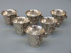 A set of six Chinese white metal tot cups with applied prunus decoration,