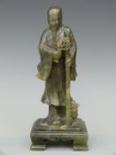 A Chinese carved spinach jade/jadeite figure of an elderly gentleman holding flowers,