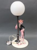A vintage table lamp in the form of a suited Pink Panther leaning against a lamp post,