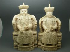 A pair of Chinese carved ivory figures in the form of an emperor and empress seated on thrones,