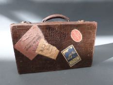 A tan leather mock crocodile suitcase with vintage travel labels, approximately 40cm long.