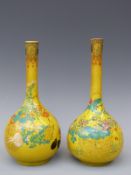 A pair of Chinese earthenware/enamelled bottle vases with flowers on a yellow ground, 24.