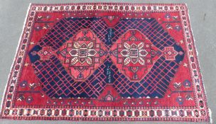 A Persian Shzad hand made red ground rug with stylised flowers to corners and Islamic script to