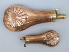 Two copper and brass powder flasks both with embossed decoration, 19cm and 12cm long.