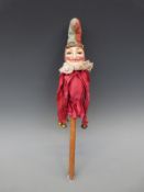 A papier mache jester doll on wooden pole