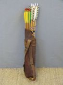 Eighteen wooden archery arrows some with feather flights, in brown leather quiver.