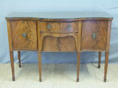 An Edwardian Sheraton style flame mahogany sideboard with serpentine front on tapering spade