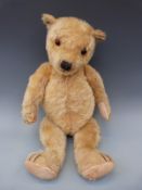 A vintage mohair teddy bear with glass eyes, cocked wrists and 90° feet,