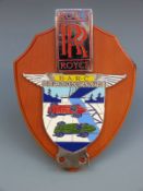 A BARC Brooklands badge and Rolls Royce badge on wooden base,