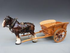 A ceramic model of a Shire horse in harness with wooden cart