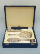 A cased hallmarked silver three piece dressing table set comprising mirror and two brushes,