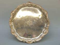 A hallmarked silver salver with shell rim raised on three ball and claw feet, Sheffield 1899,