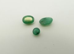 Two oval cut emeralds the largest approximately 0.72ct and a round cut emerald of approximately 0.