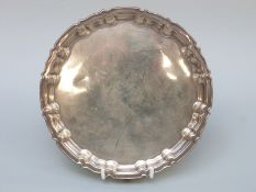 A George V hallmarked silver salver with shaped edge, raised on three feet,